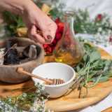 Prontamente l�esperta prepara tutto il necessario per il secondo rituale, quello del corpo. La vediamo posizionare su una tavolozza di legno una coppetta con miele e cannella, il mazzetto con le erbe che aveva fatto bruciare durante il primo massaggio e una boccetta con olio d�oliva